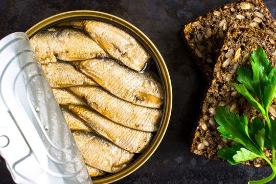 lata de sardinas en conserva sobre fondo oscuro con pan